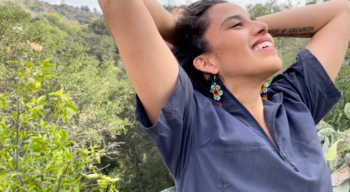 Yvette smiling outdoors among green hills