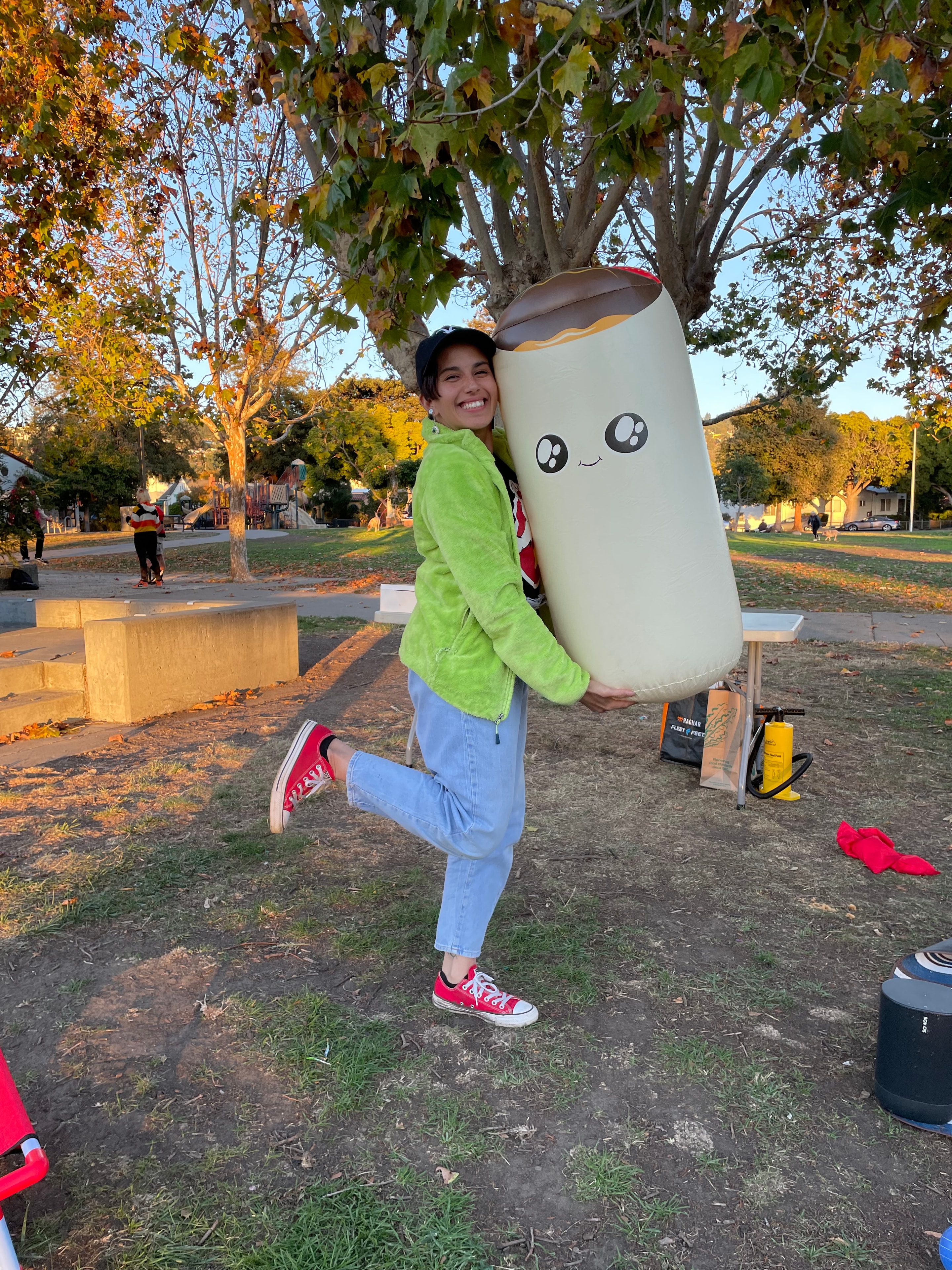 Yvette outdoors carrying a playful oversized prop in a park