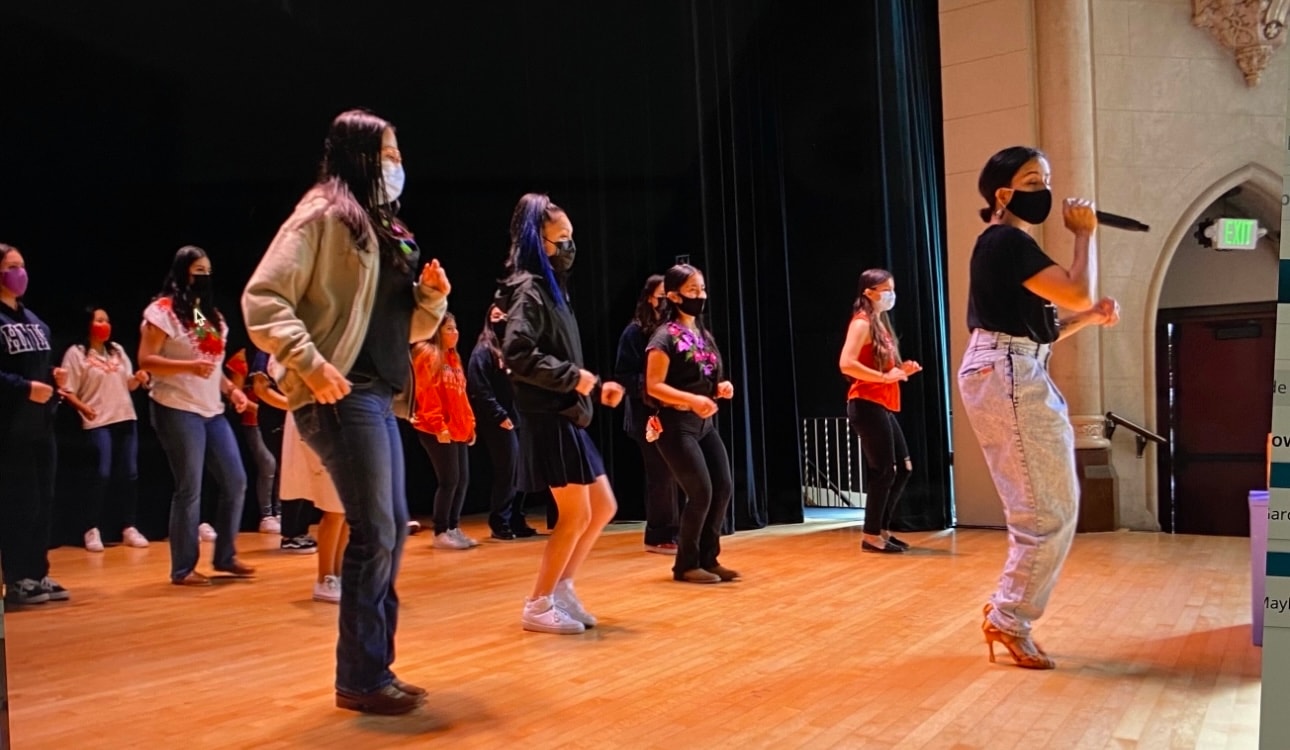 Yvette leading a group dance rehearsal on stage